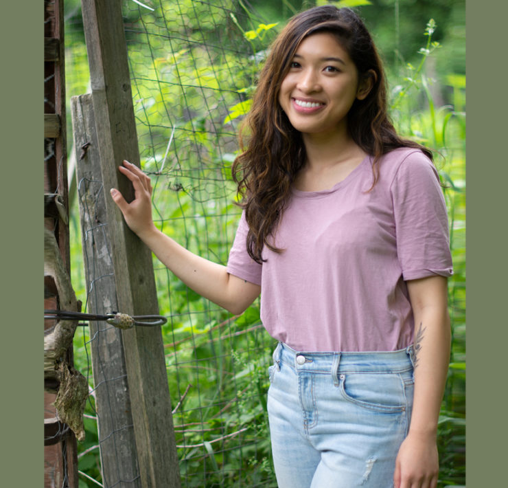 Woman standing next to a fence post in a garden