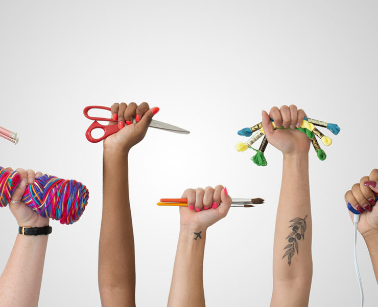 7 raised hands holding crafting gear